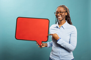 Joyful african american woman gesturing to blank speech bubble, expressing excitement over product....