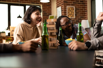 African american and caucasian women laughing hysterically at joke, seated at table with drinks and bowl of chips. The cheerful duo enjoys lively conversation, bonding with friends in fun atmosphere.