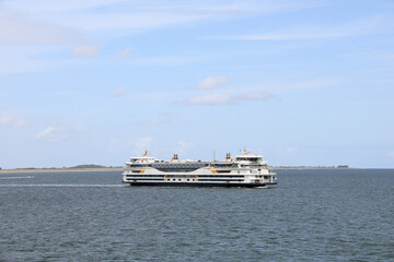 Ferry boat navigating across calm waters with a clear blue sky and distant land visible, showcasing...