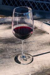 Elegant glass of red wine resting on an oak barrel at a winery