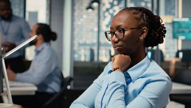 Trader frowning while looking at investment portfolio candlestick charts after unexpected market crash. African american woman upset by stock exchange account losses - Powered by Adobe