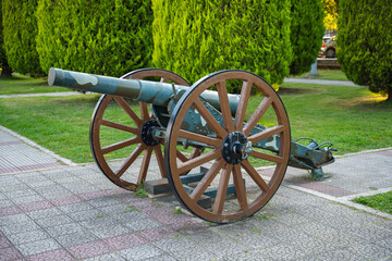 Historic military cannon on display in public park museum. Old war artillery cannon with wooden...