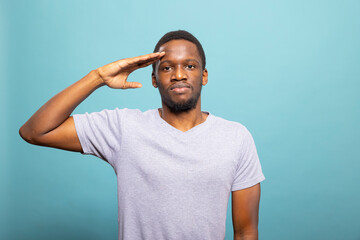 Black man doing a military salute and looking at camera, showing honor and respect to veterans....