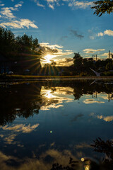 Fototapeta premium Sunset reflecting on water surface with clouds and trees