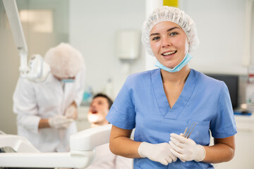 Young girl doctor in blue suit cooperates with clinic, works as general practitioner in dental...