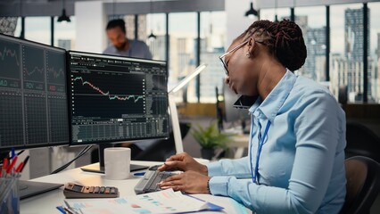 Equity analyst in office reviews quarterly earnings paperwork to assess future stock market value, talking on phone. Trader making calls, conducting financial analysis to improve investments