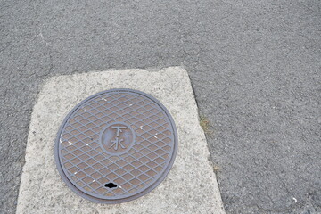 道路に設置された下水マンホールの蓋と舗装面