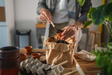 Gardener filling terracotta pots with potting soil using a small shovel