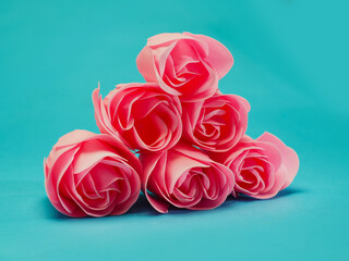 A bunch of pink roses are arranged in a pyramid shape on a blue background. The arrangement gives...