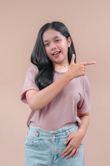 An Asian woman in casual outfit smiling brightly while pointing sideways with playful confidence, showing positive energy and charm for modern lifestyle concepts.
