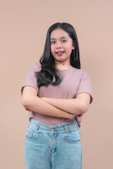 A young Asian woman with long black hair poses confidently with folded arms, wearing a casual pink t-shirt and light blue jeans against a plain background.