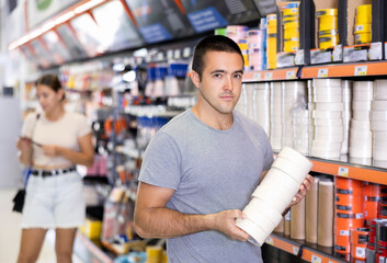 Man buys sticky adhesive tape in construction store for carrying out internal and external...