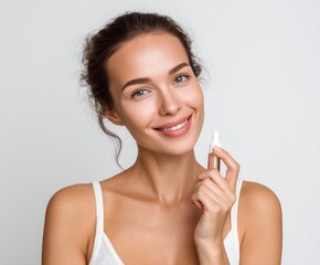 A woman with a radiant smile holds a serum bottle, showcasing healthy, glowing skin.