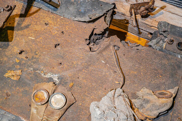 Interior scene on rusted metal ground littered with debris, construction items, and a small...