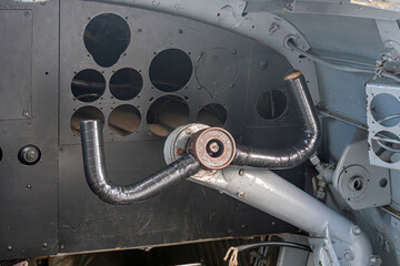 Close-up view of an industrial aircraft cabin, focusing on a metallic cylinder with circular holes...