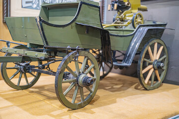 Vintage olive green motorized reconnaissance vehicle no horses in a museum setting, with four...