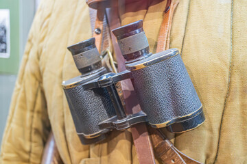 Close-up of two mounted binoculars, leather strap or material, open lens caps, central hinge,...