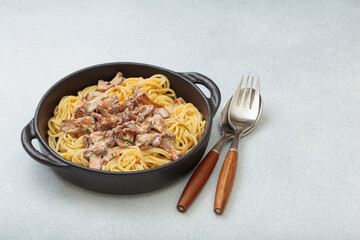 Spaghetti with creamy chanterelle mushroom sauce served in a cast iron pan, accompanied by a fork...