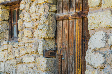 Ancient Central European village scene with a weathered green wooden door in a stone wall,...