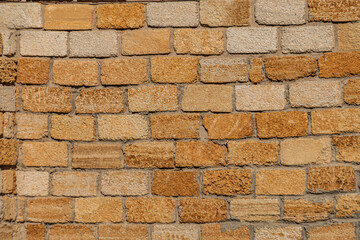 Close-up of weathered light brown bricks in an ancient Central European village, naturally lit with a warm glow The brickwork is laid evenly without mortar lines