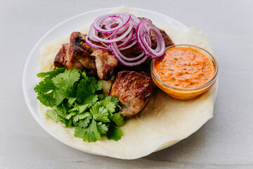 Grilled pork kebab with fresh herbs, red onion, lavash and spicy red pepper sauce