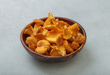 Fresh chanterelle mushrooms in a rustic wooden bowl, on a gray background, a warm and inviting autumnal scene perfect for culinary uses