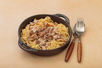 Spaghetti with creamy chanterelle mushroom sauce served in a cast iron pan, accompanied by a fork...