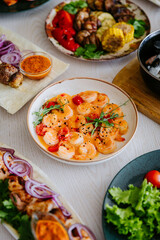 Shrimp in creamy spicy sauce with cherry tomatoes and herbs in ceramic bowl