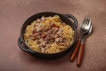 Spaghetti with creamy chanterelle mushroom sauce served in a cast iron pan, accompanied by a fork...