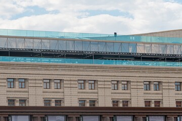 Obraz premium Close-up of a modern, multi-story building under construction, featuring concrete beams, columns, and expanses of windows Blue protective material on the roof suggests ongoing work such as waterproo