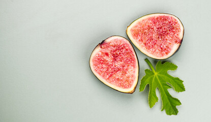 Fig fruits. Half of Ripe sweet fresh figs fruit with leaf close up, on pastel green background, flat lay, top view. Border art design 