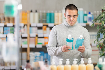 Male shopper chooses best mouthwash in supermarket