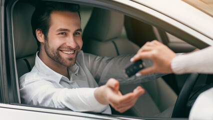 Close up female hand gives car key to male hand in dealership. Car industry, insurance or...