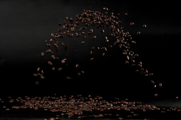 Coffee beans flying splashing in mid air. Black background isolated element. Many Coffee Beans...