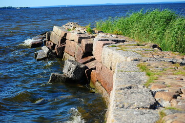 stone dam by the seashore. Large granite blocks form a massive fortification that extends into the...
