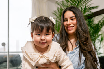 Young mother holding her baby girl at home