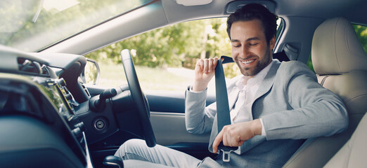Close auto seat belt, sitting inside transport before driving and go on safe journey. Male driver fastening his seat belt. Happy young caucasian man in suit attaches car's seat belt in cabin transport