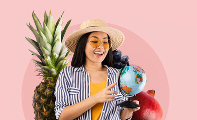 A woman smiles and points at a globe while surrounded by fresh fruits including pineapple and...