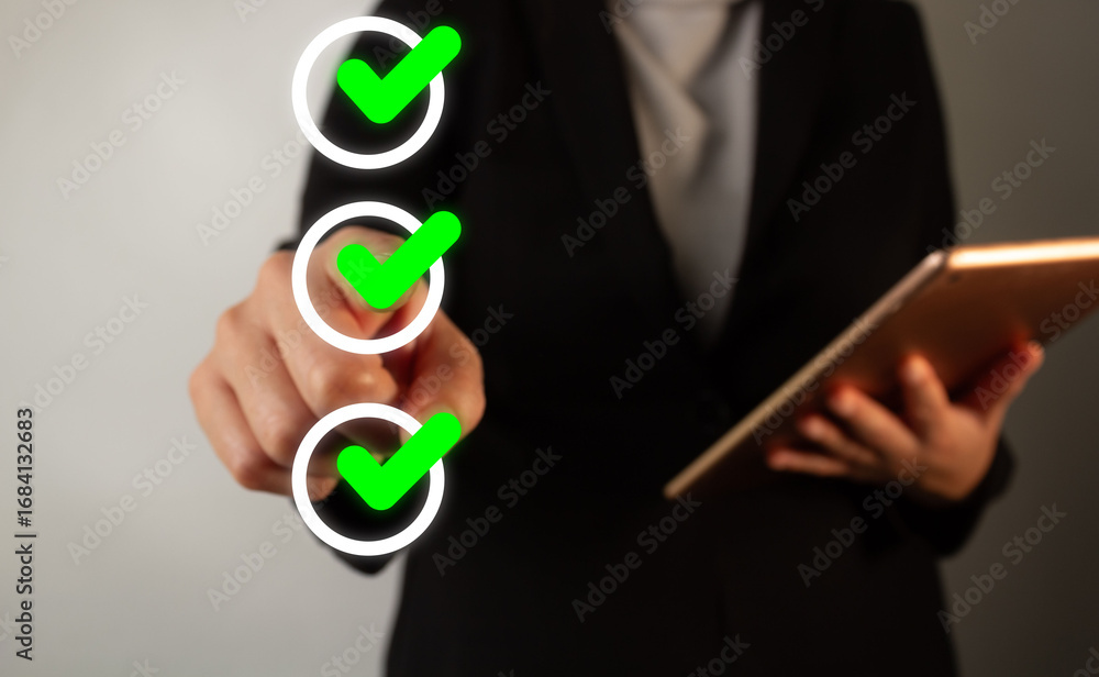 Poster businessman holding a tablet while pointing towards a check mark of a group