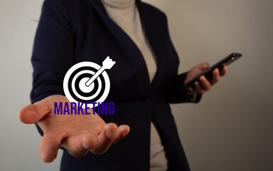 Marketing Objectives: Businesswoman holding a target with the word marketing in her hand