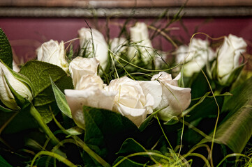 A bouquet of white roses surrounded by green foliage and ornamental grass. 