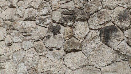 Textured stone wall composed of irregularly shaped rocks fitted together in natural relief. Perfect for use as a rugged background, architectural mockup, or design texture.