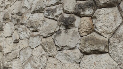 Textured stone wall composed of irregularly shaped rocks fitted together in natural relief. Perfect for use as a rugged background, architectural mockup, or design texture.