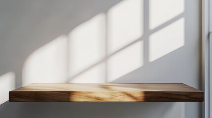 Empty copy space image of a wooden plank on a white wall background illuminated by sunlight casting a tree shadow Ideal for presenting products in a mockup scene