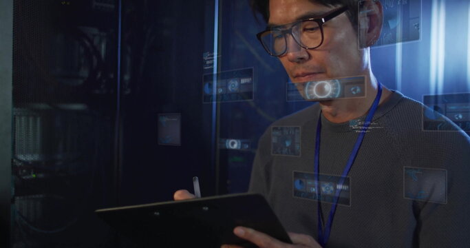 Korean technician monitoring server racks in server room, with tablet stylus and holograms