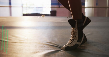 Balancing athlete showing legs in high-top shoes on padded mat with ropes and windows, copy space