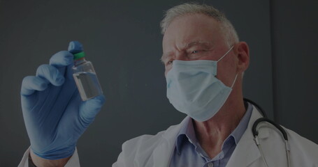 Senior male doctor in lab coat inspecting clear vial at clinic, with stethoscope gloves and mask