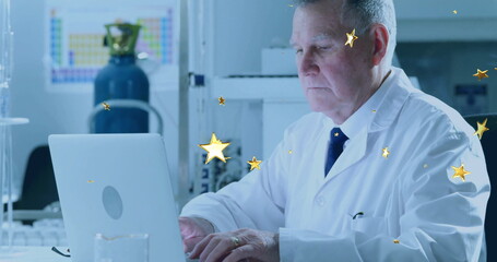 Typing senior scientist wearing lab coat and tie at laboratory bench, with laptop and gas cylinder