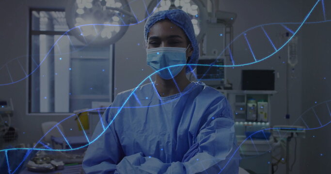 Standing female surgeon wearing surgical attire, crossing arms in operating room with DNA overlay