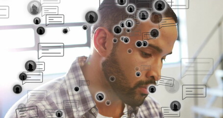 Working man wearing plaid shirt typing on laptop at office desk, with chat bubbles, avatar icons